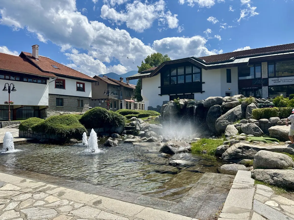 The main square in Bansko, with fountains, stone paving and traditional white and timber buildings